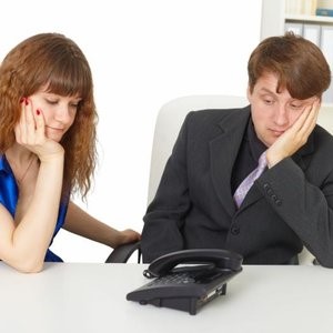 man and woman in office waiting for the phone to ring